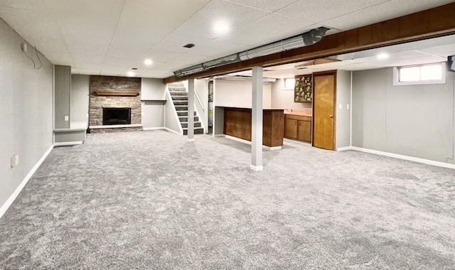 below grade area featuring stairs, a fireplace, baseboards, and carpet flooring