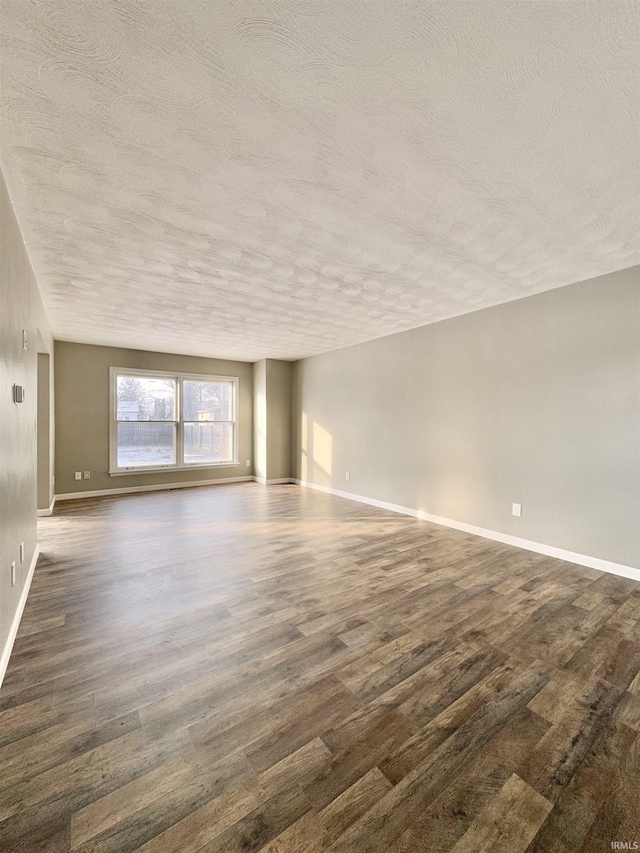 unfurnished living room featuring a textured ceiling, dark wood finished floors, and baseboards