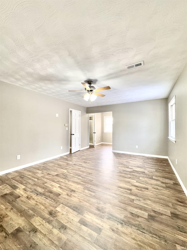 unfurnished room with baseboards, ceiling fan, visible vents, and wood finished floors