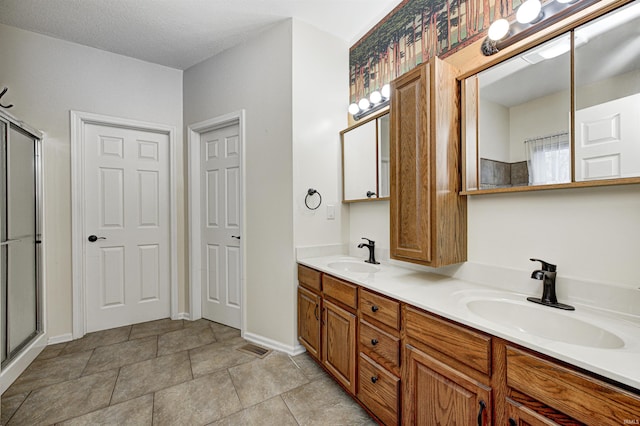 bathroom with vanity, an enclosed shower, and a textured ceiling