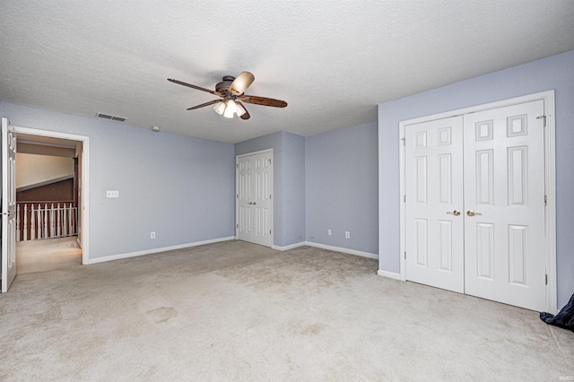 unfurnished bedroom featuring a textured ceiling, light colored carpet, and ceiling fan