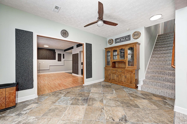 unfurnished living room featuring ceiling fan and a textured ceiling