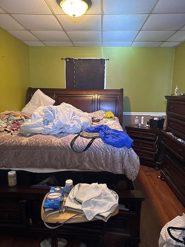 bedroom with dark wood-type flooring and a drop ceiling