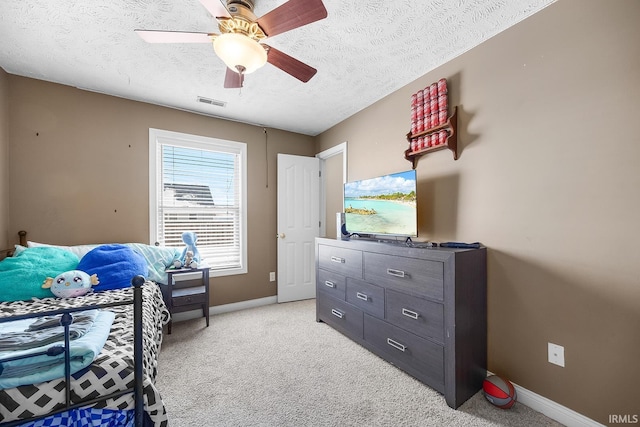 carpeted bedroom featuring ceiling fan and a textured ceiling