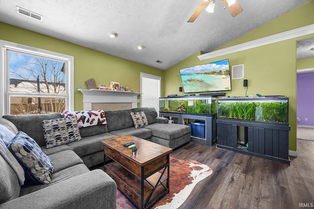 living room with lofted ceiling, dark hardwood / wood-style flooring, ceiling fan, a textured ceiling, and a tiled fireplace