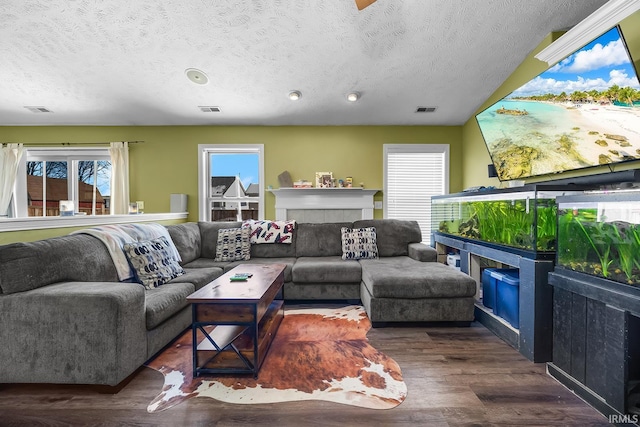 living room featuring a tiled fireplace, dark hardwood / wood-style floors, and a textured ceiling