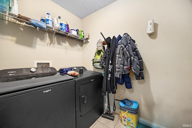 clothes washing area featuring independent washer and dryer, light tile patterned floors, and a textured ceiling