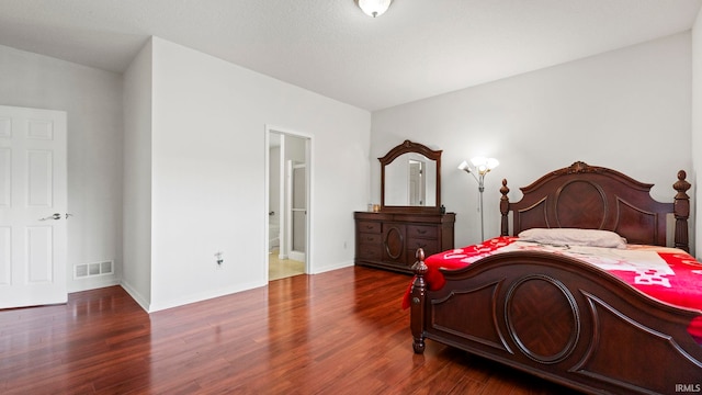 bedroom with ensuite bathroom and dark hardwood / wood-style floors