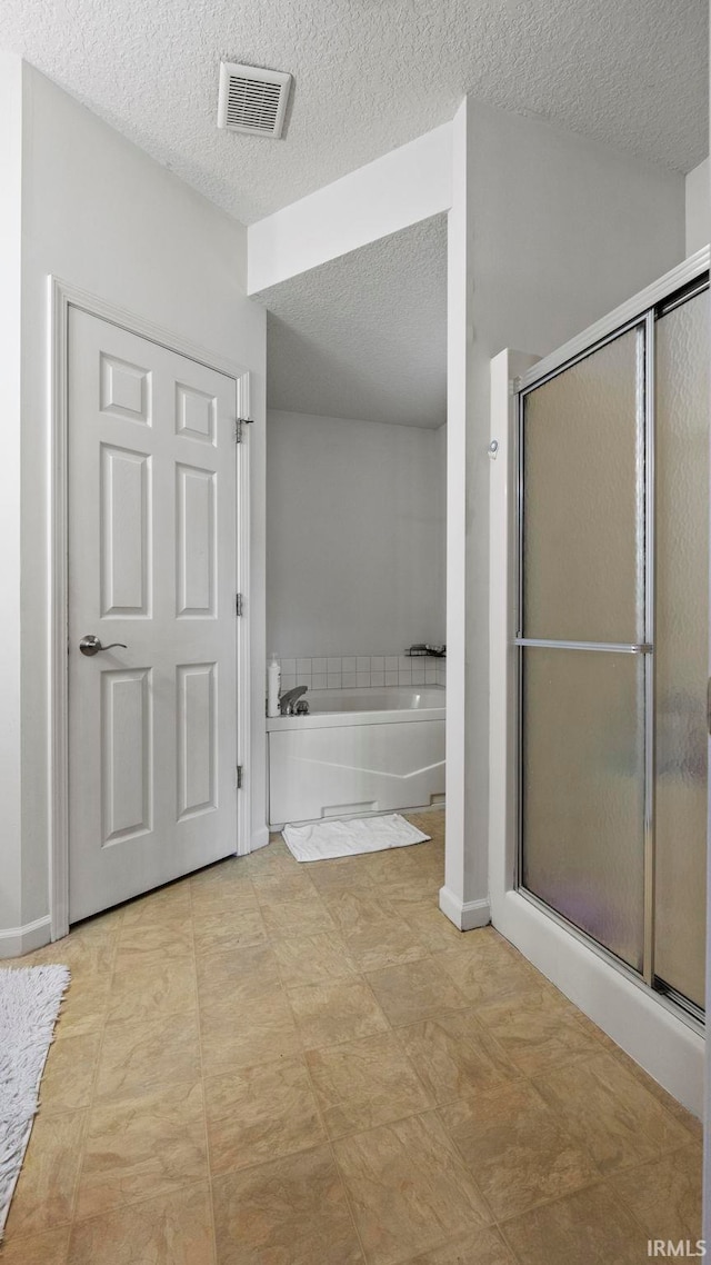 bathroom featuring independent shower and bath and a textured ceiling