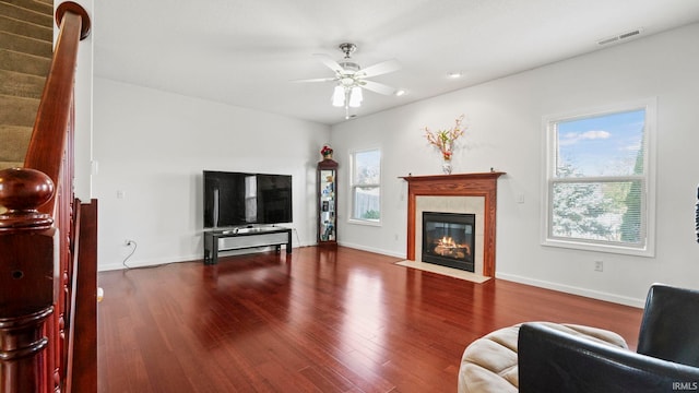 living room with a tiled fireplace, ceiling fan, hardwood / wood-style flooring, and a healthy amount of sunlight