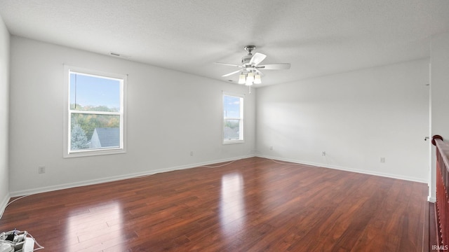 spare room featuring dark wood-type flooring, ceiling fan, and a textured ceiling