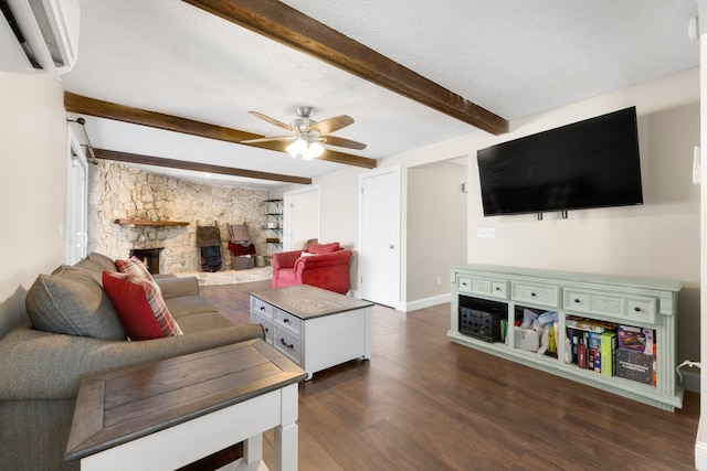 living room featuring dark wood-type flooring, beam ceiling, a wall mounted air conditioner, ceiling fan, and a fireplace