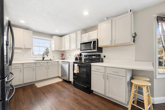 kitchen featuring sink, dark wood-type flooring, appliances with stainless steel finishes, a textured ceiling, and white cabinets