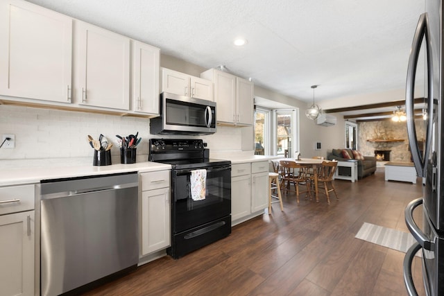 kitchen with a stone fireplace, appliances with stainless steel finishes, dark hardwood / wood-style floors, white cabinets, and backsplash