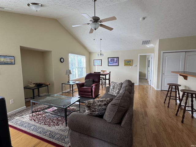 living room featuring ceiling fan, lofted ceiling, wood-type flooring, and a textured ceiling