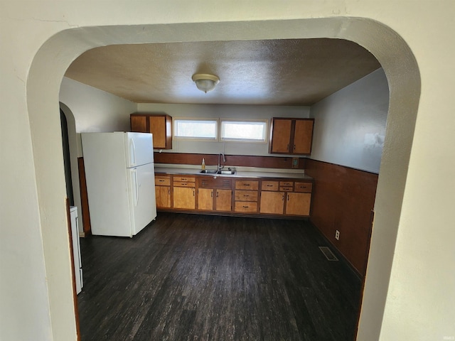 kitchen featuring dark hardwood / wood-style floors, sink, white fridge, and a textured ceiling