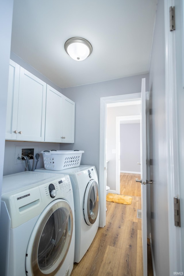 laundry room featuring separate washer and dryer, light hardwood / wood-style flooring, and cabinets