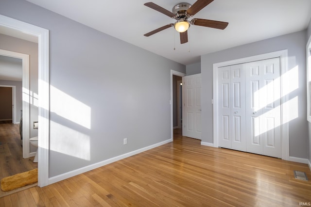 unfurnished bedroom featuring ceiling fan, ensuite bath, a closet, and light wood-type flooring