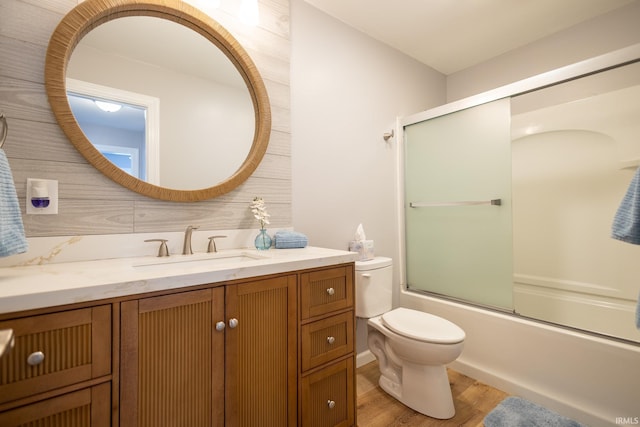 full bathroom featuring vanity, hardwood / wood-style floors, enclosed tub / shower combo, and toilet