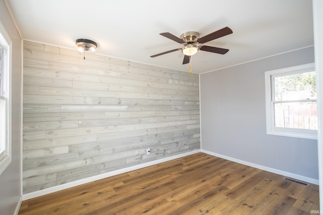 spare room with ceiling fan, dark hardwood / wood-style flooring, and wood walls