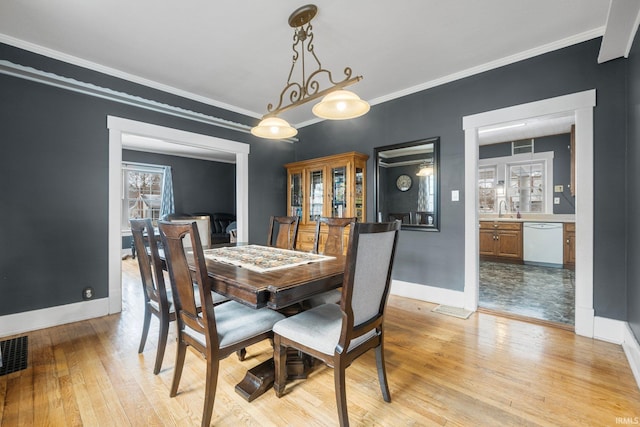 dining room with ornamental molding and light hardwood / wood-style flooring