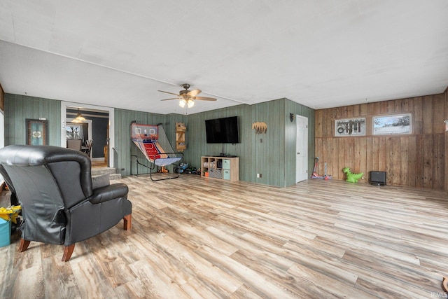 living room featuring hardwood / wood-style flooring, ceiling fan, and wood walls