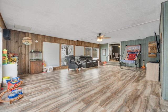 living room featuring wooden walls, light hardwood / wood-style floors, and ceiling fan