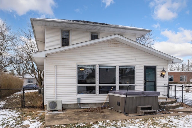 snow covered rear of property featuring a hot tub, ac unit, and central air condition unit