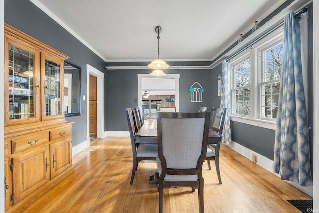 dining area with crown molding and light hardwood / wood-style flooring