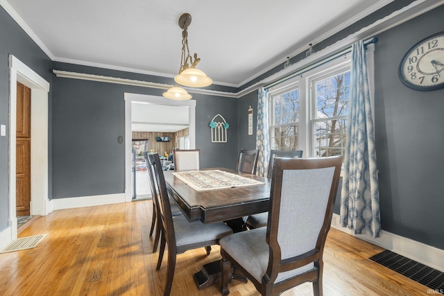 dining space with ornamental molding and light hardwood / wood-style flooring