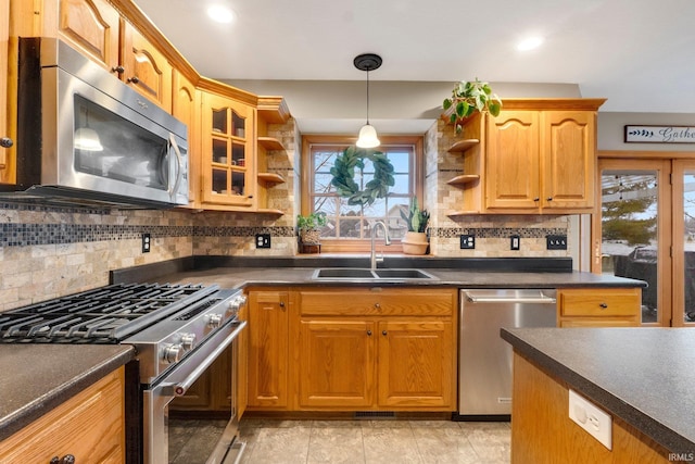 kitchen with appliances with stainless steel finishes, sink, pendant lighting, and backsplash