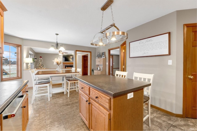 kitchen with a breakfast bar, an inviting chandelier, a center island, stainless steel dishwasher, and pendant lighting