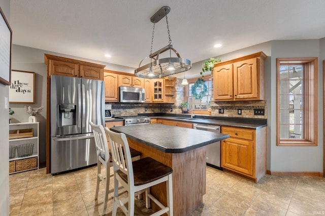 kitchen with pendant lighting, appliances with stainless steel finishes, backsplash, a kitchen breakfast bar, and a kitchen island