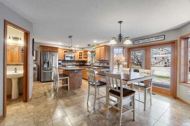 dining space featuring an inviting chandelier, sink, and a textured ceiling