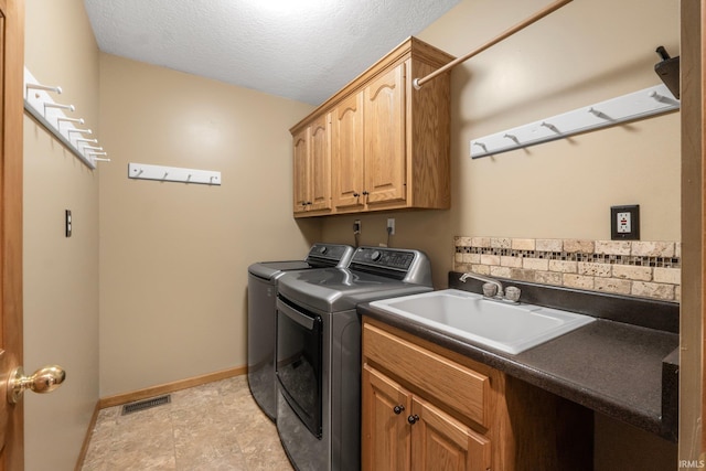 laundry area with cabinets, sink, washing machine and dryer, and a textured ceiling