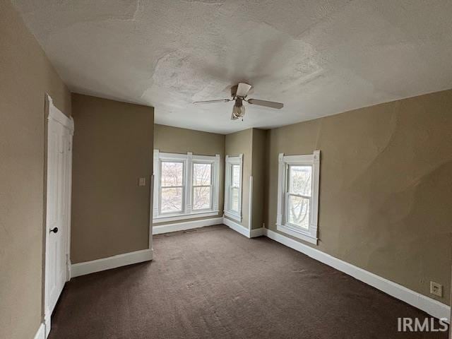 unfurnished bedroom with ceiling fan, carpet floors, multiple windows, and a textured ceiling