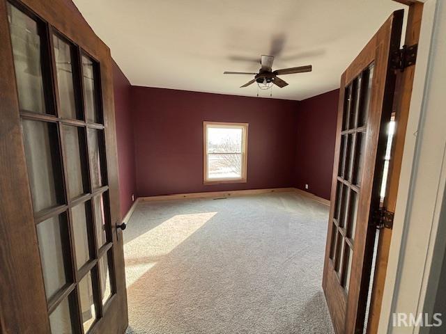 carpeted empty room with french doors and ceiling fan