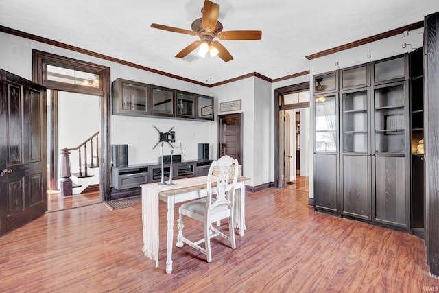 kitchen with ceiling fan, light wood finished floors, glass insert cabinets, and crown molding