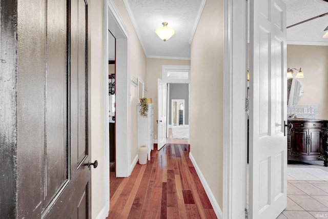 hall with crown molding, wood-type flooring, and a textured ceiling