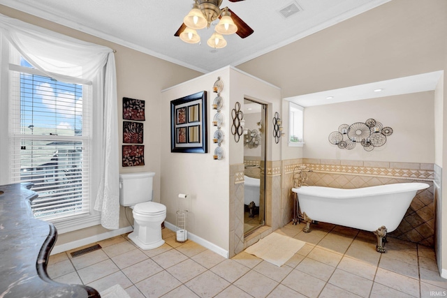 bathroom featuring tile patterned flooring, a healthy amount of sunlight, ornamental molding, and tile walls