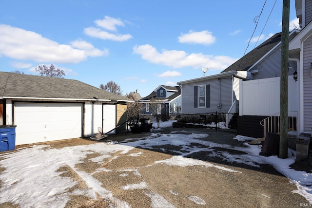 view of snow covered exterior featuring a garage and an outbuilding