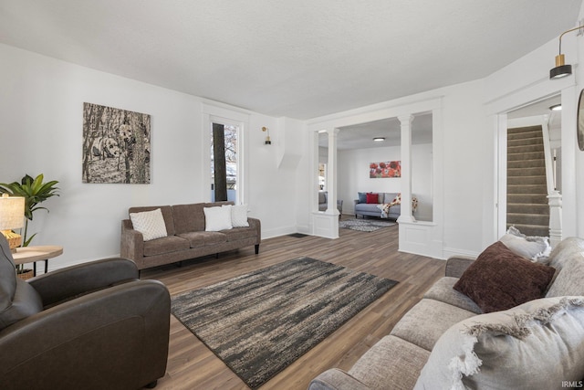 living room featuring dark hardwood / wood-style floors, a textured ceiling, and ornate columns