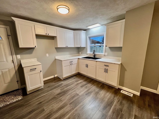 kitchen with dark hardwood / wood-style flooring, sink, white cabinets, and a textured ceiling