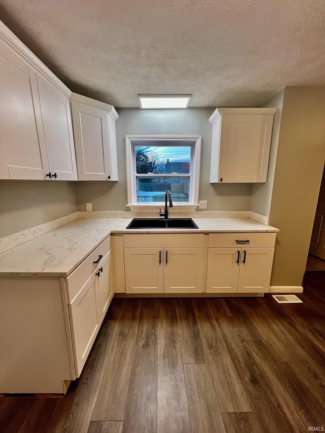 kitchen featuring dark hardwood / wood-style flooring, sink, a textured ceiling, and white cabinets