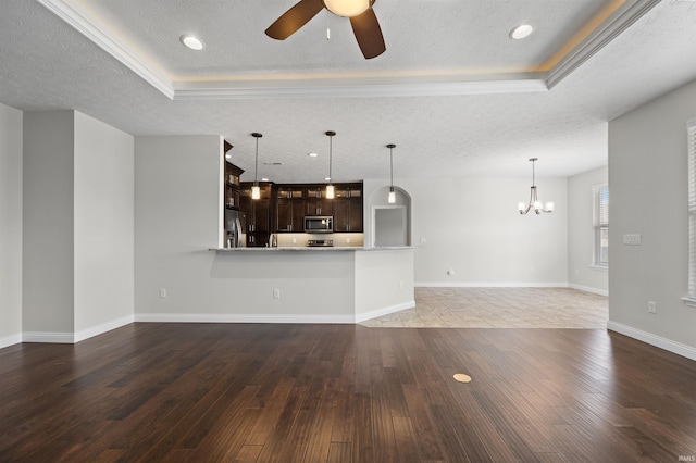 unfurnished living room with dark hardwood / wood-style flooring, a tray ceiling, ceiling fan with notable chandelier, and a textured ceiling