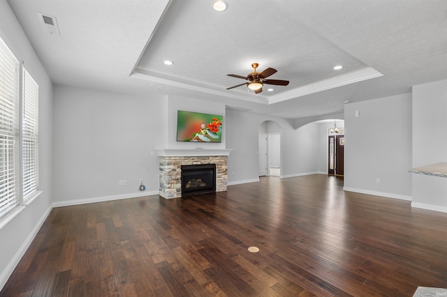 unfurnished living room featuring dark wood-type flooring, ceiling fan, a fireplace, and a raised ceiling