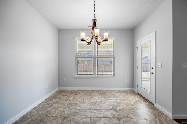 unfurnished dining area with a chandelier and a textured ceiling