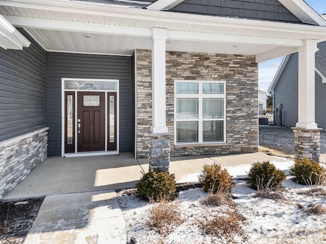 snow covered property entrance with a porch