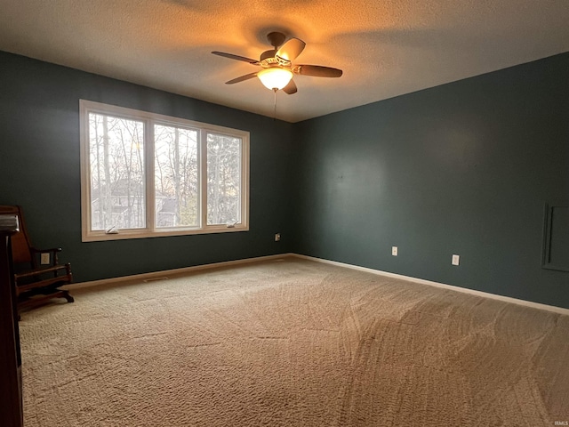 carpeted empty room with ceiling fan and a textured ceiling