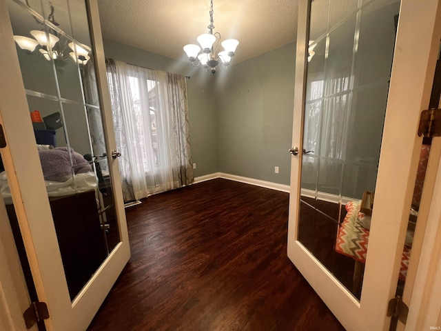 interior space featuring an inviting chandelier, dark hardwood / wood-style floors, and french doors